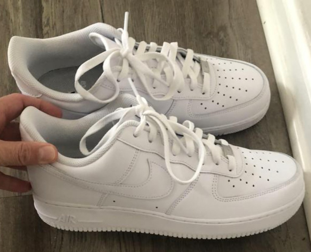 hand holding a pair of white air force 1s