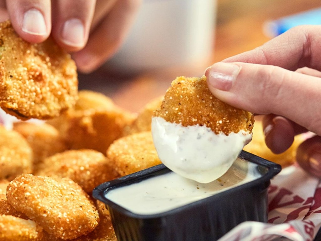 dipping a fried pickle into sauce