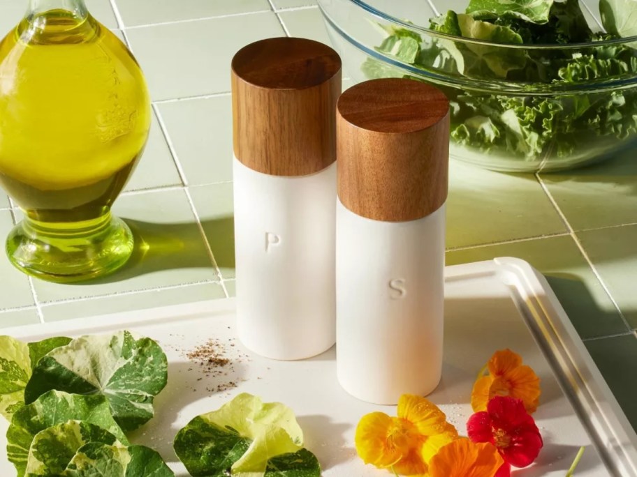 white and wood salt and pepper grinders on a cutting board with food