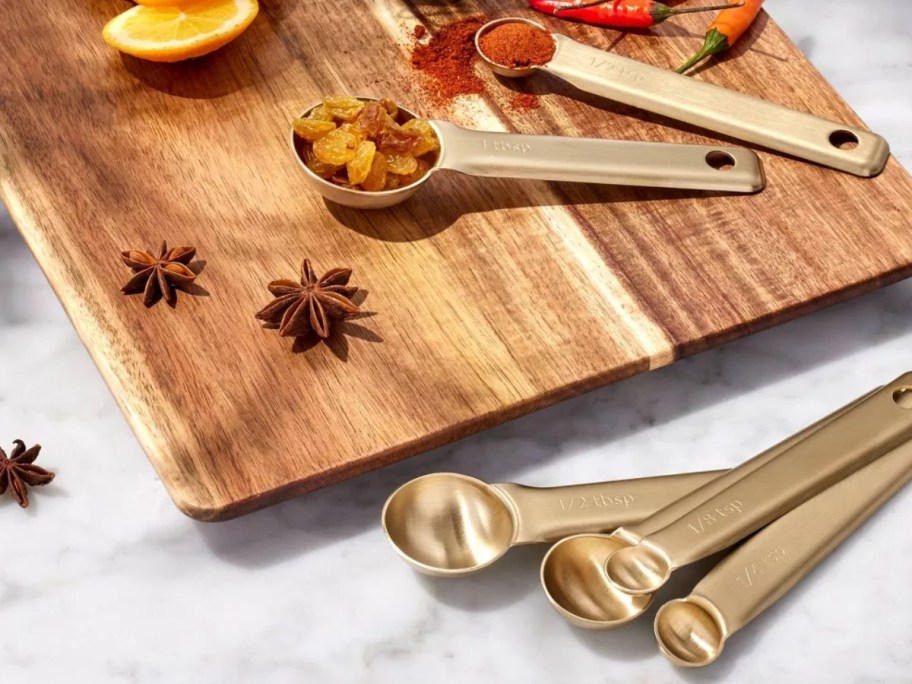 gold color measuring spoons on a cutting board