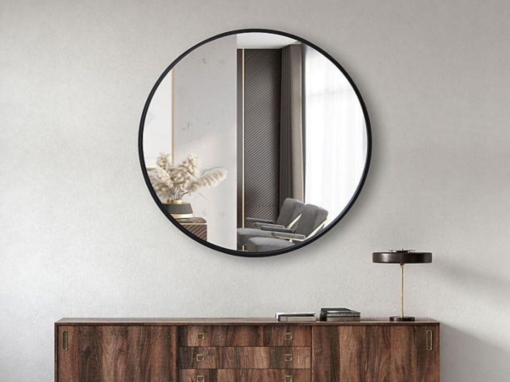 large round black wall mirror on wall above console table