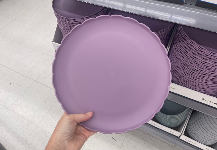 hand holding a lavender scallop edge plastic dinner plate at Walmart