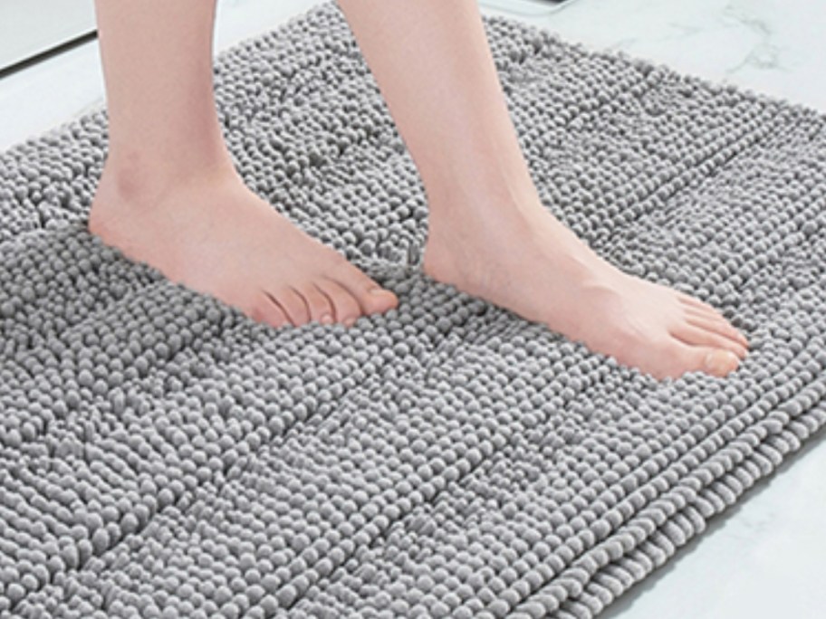 woman's bare feet stepping onto a gray chenille bubble baht mat