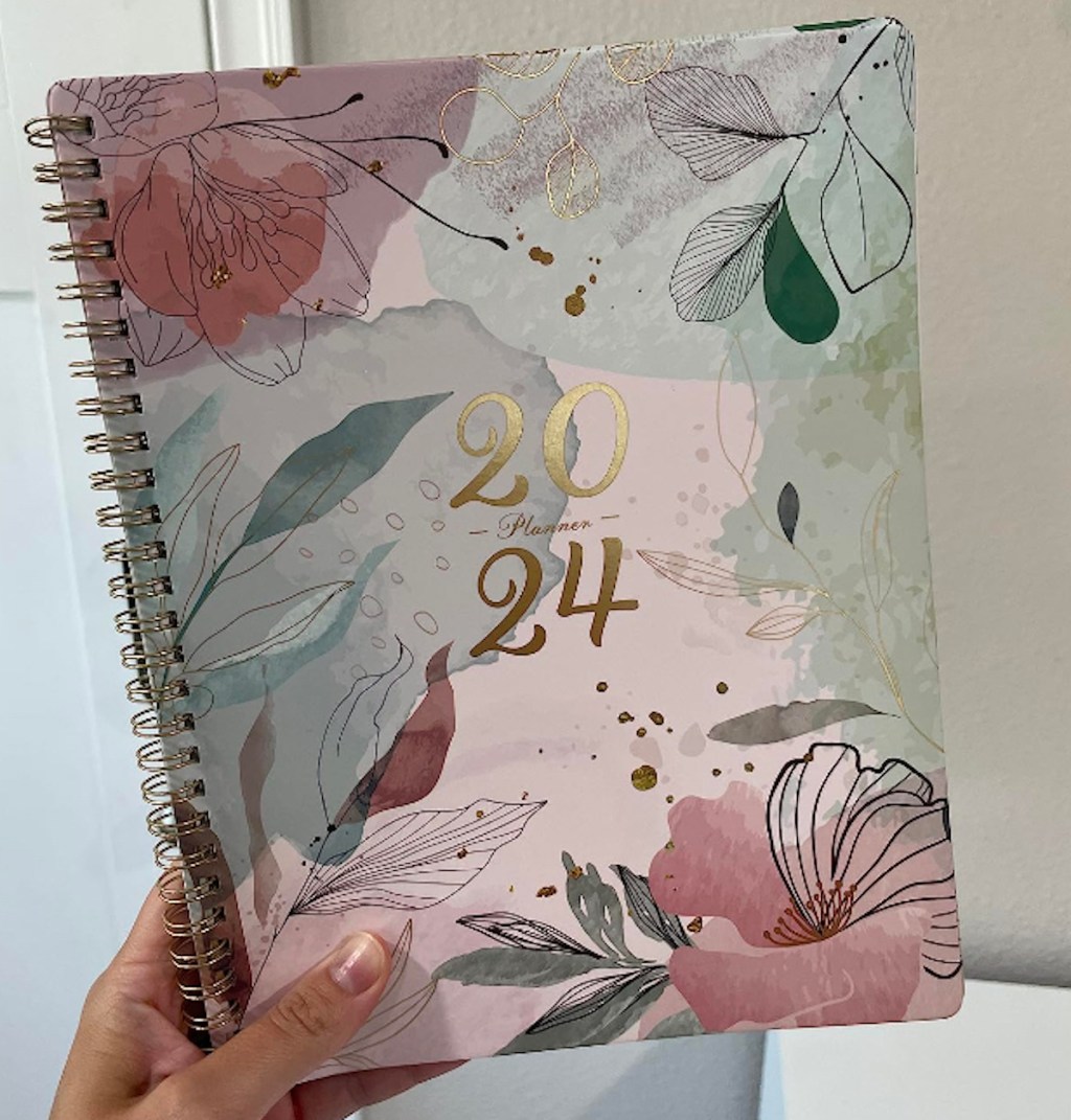 Hand holding a 2024 planner with flowers on the front