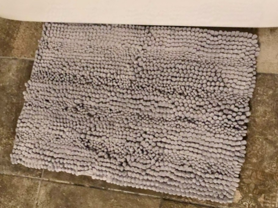 light grey chenille bubble style bath mat laying on bathroom floor