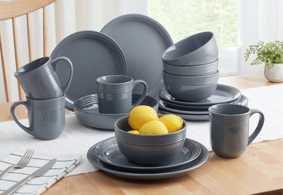 set of grey stoneware dinnerware plates, bowls and mugs sitting on a kitchen table