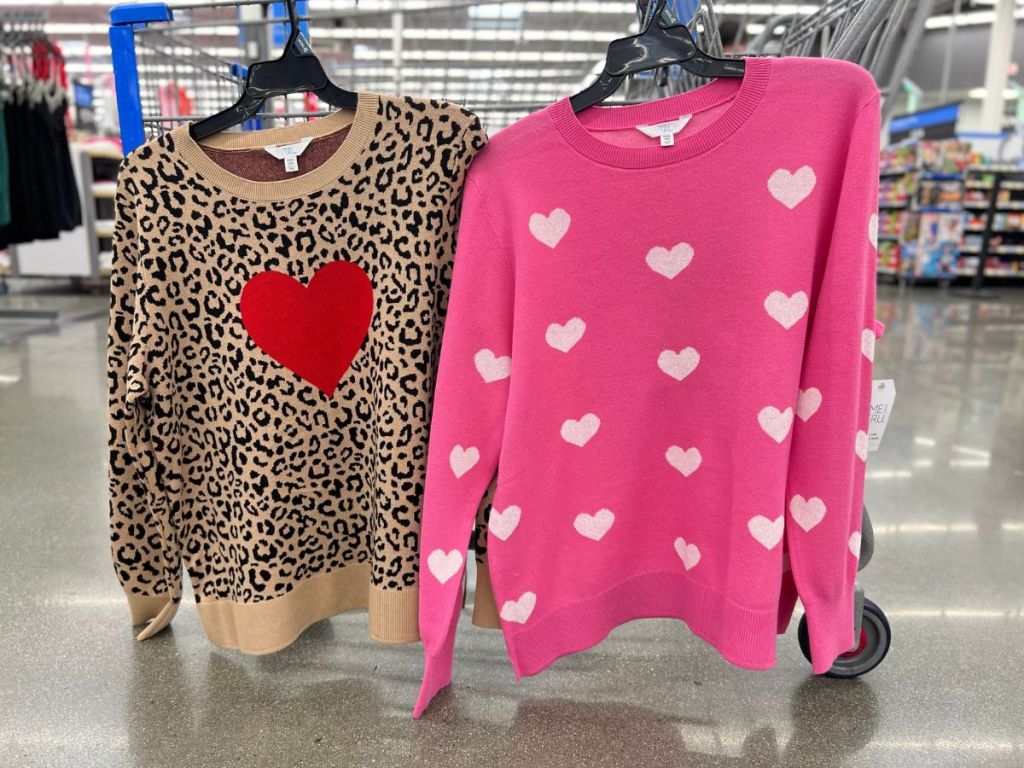 animal print with red heart and pink with white hearts sweaters hanging on rack at Walmart
