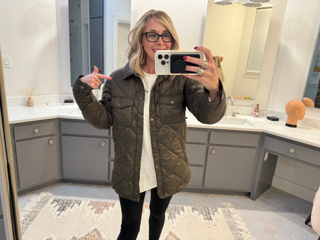 Woman taking selfie and mirror wearing green quilted jacket