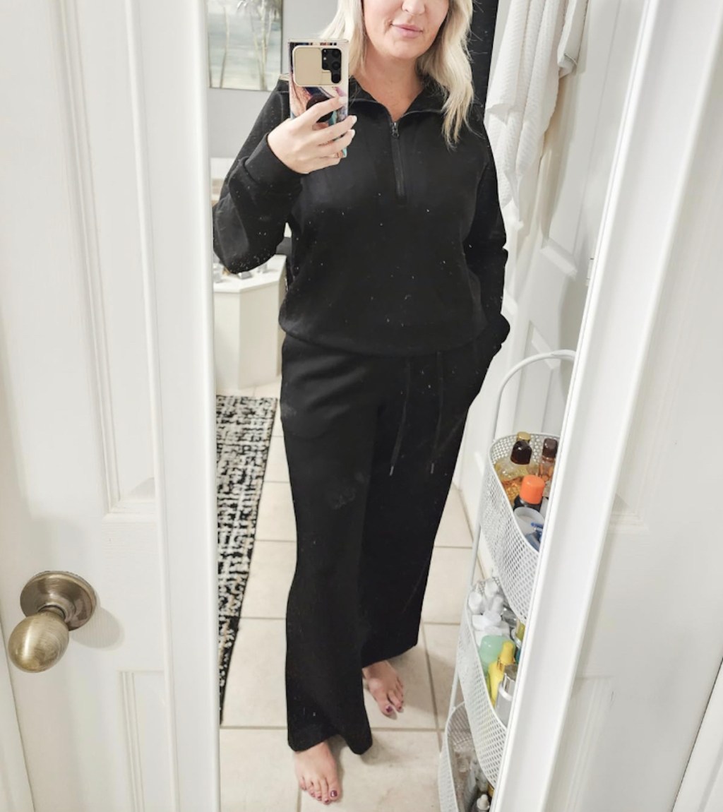 Woman taking selfie in mirror wearing black sweatsuit