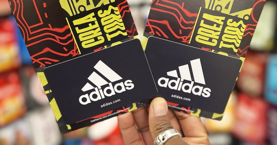 hand holding up two adidas gift cards