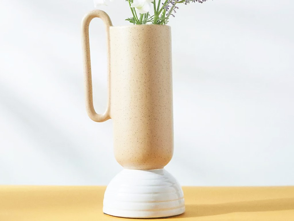 orange speckled vase with handle and white base