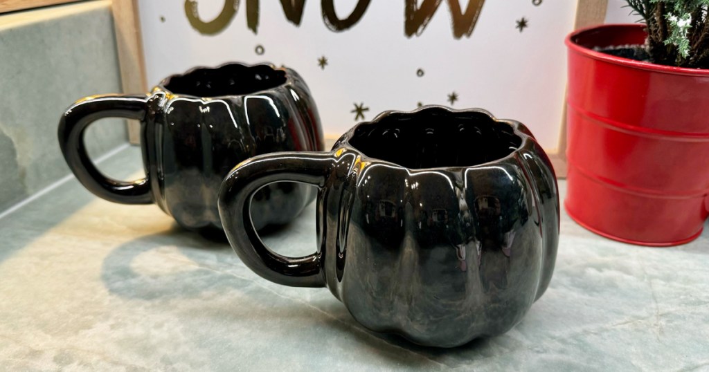 two black pumpkin shaped mugs on kitchen counter