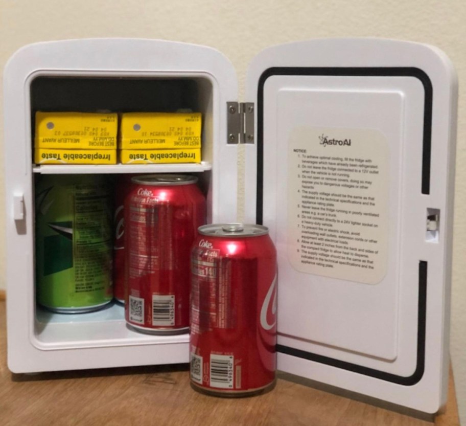 open mini fridge with soda cans inside