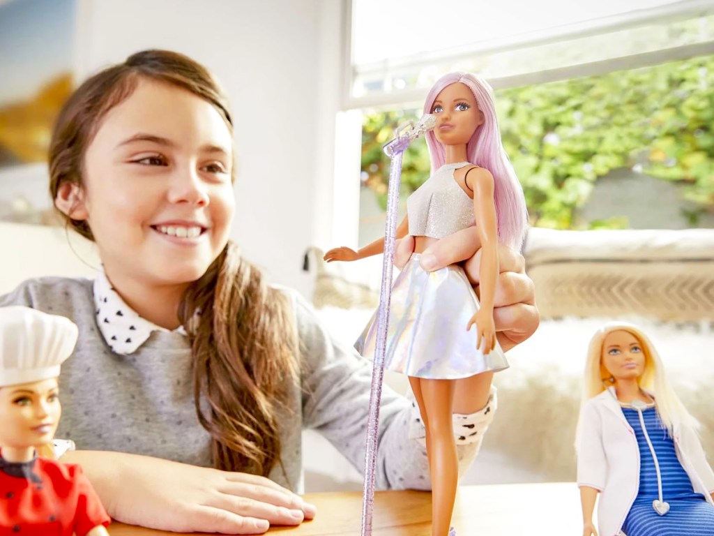 girl playing with singing Barbie doll with microphone
