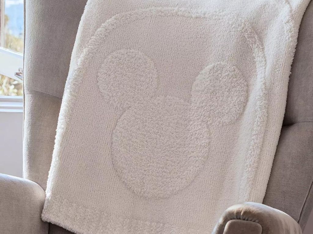The barefoot dreams disney throw draped over a chair