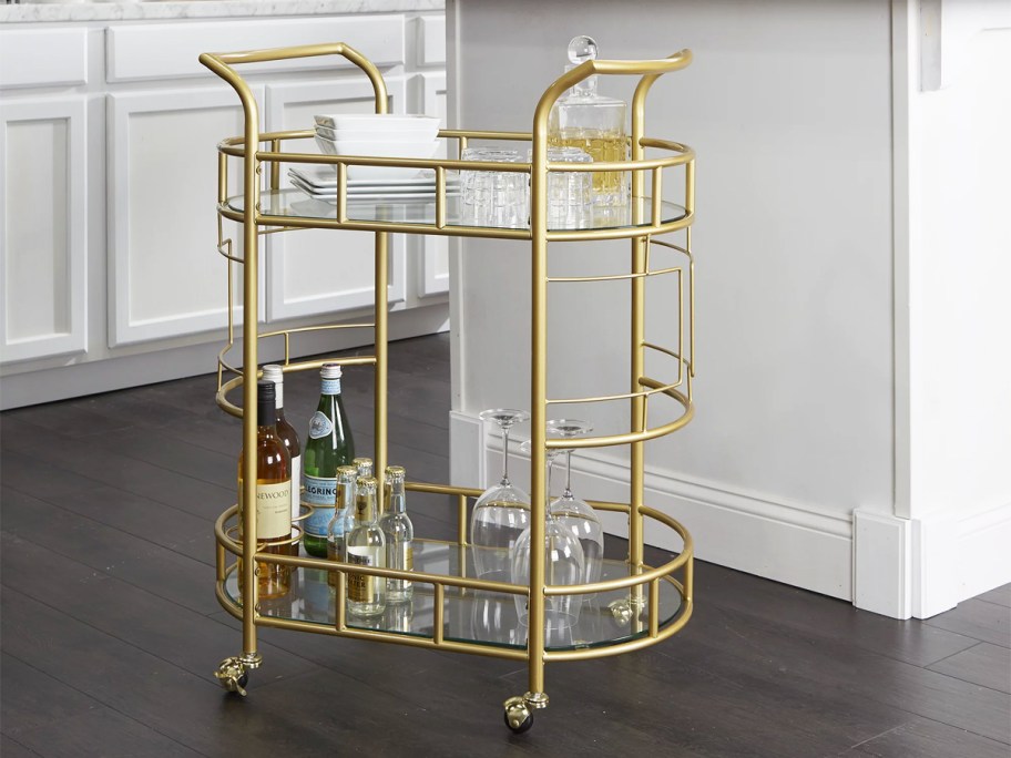 gold bar cart with glass shelves in kitchen