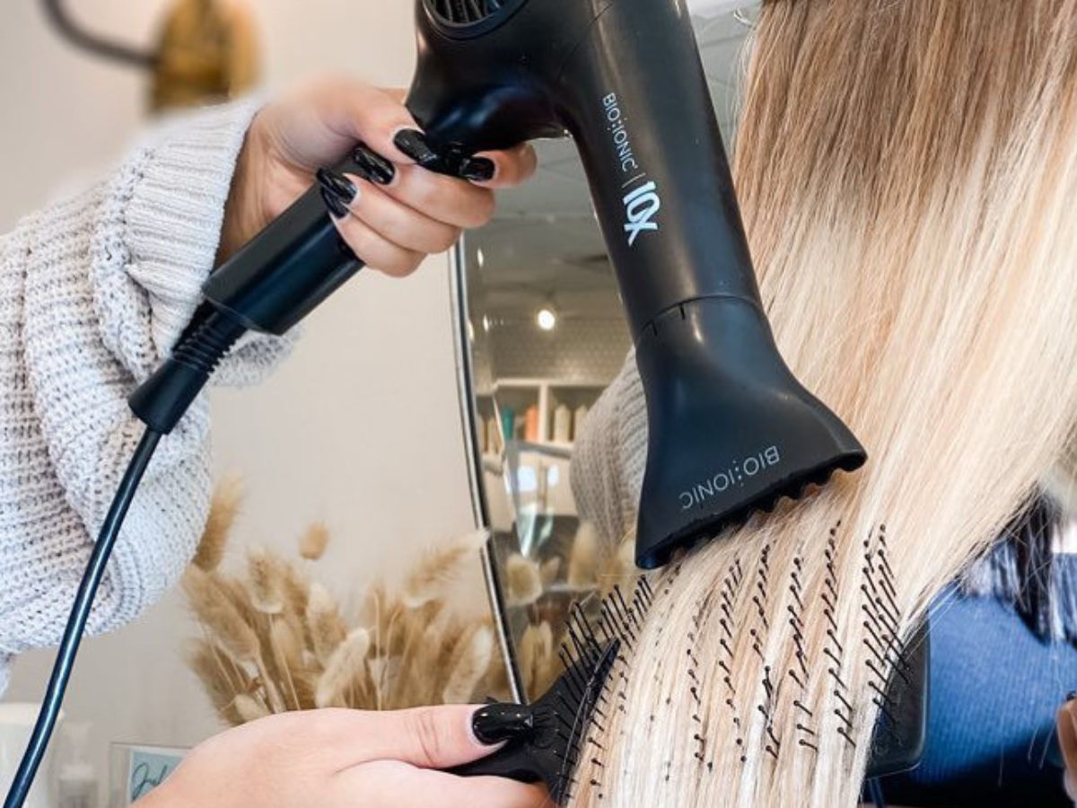 Woman using a bio ionic blow dryer on long blonde hair