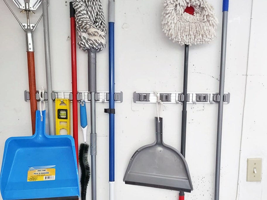 mops and dust pans hanging from wall mounted broom holders