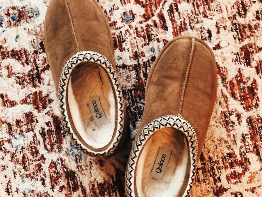 Brown slip on slippers on top of colorful area rug