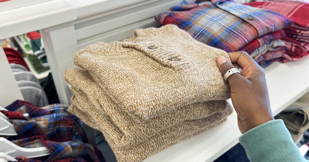 hand touching a folded sweater