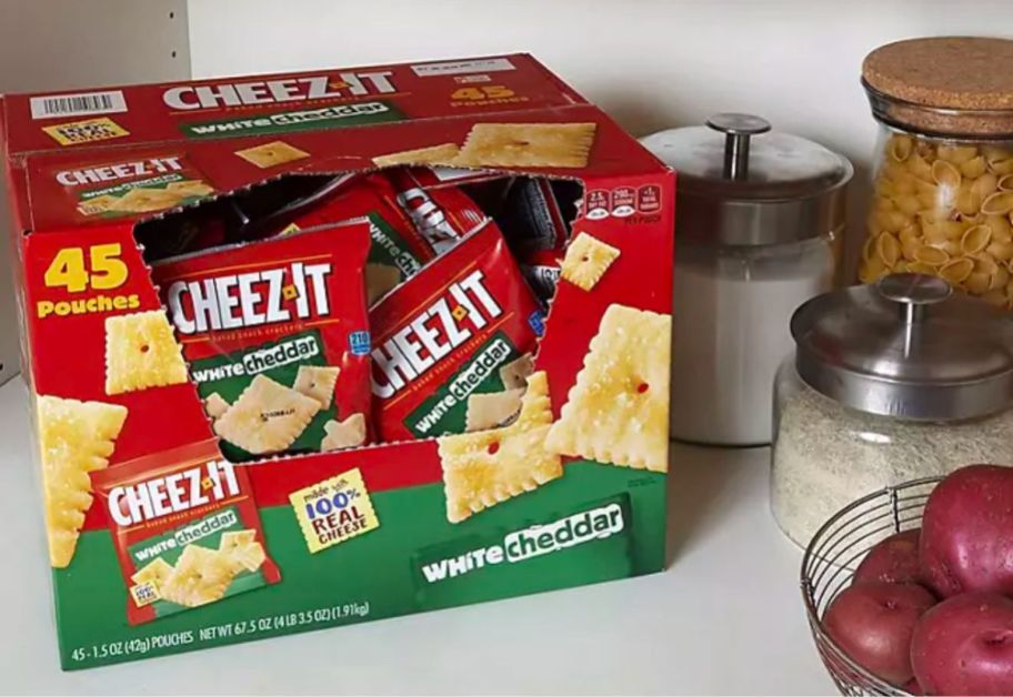 a box of Cheez-It White Cheddar Snack Packs on a kitchen counter next to a bowl of red potatoes