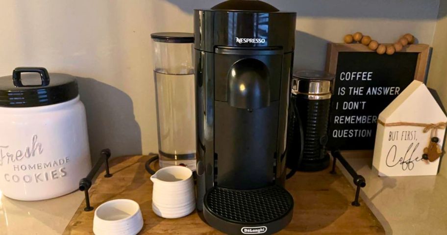 Delonghi nespresso vertuo plus set up on a kitchen counter, next to a white procelain sugar bowl