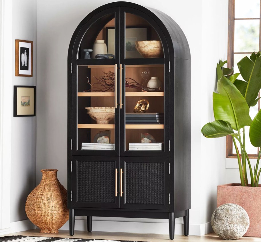 black arched storage cabinet with decor inside