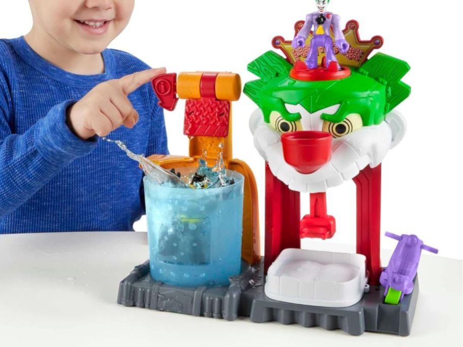 A boy playing with a Fisher-Price Imaginext DC Super Friends Batman The Joker Funhouse Playset