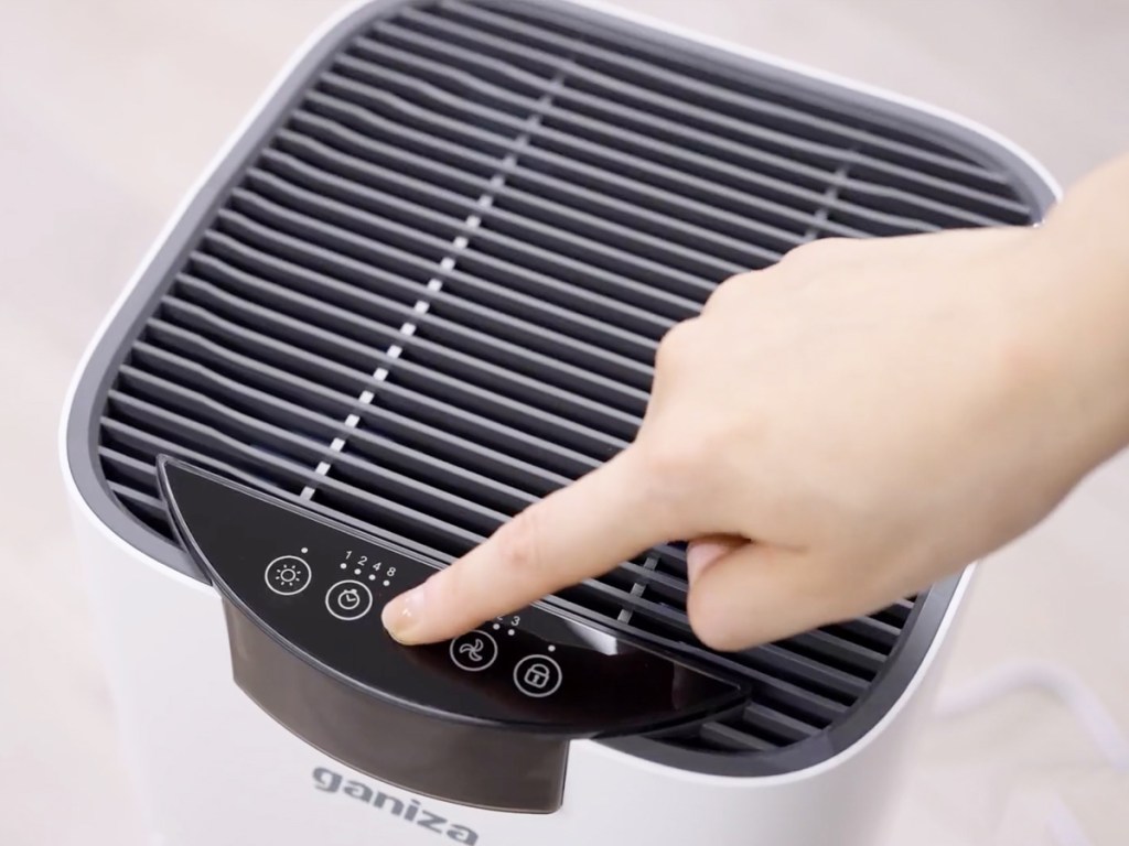 hand touching controls on top of air purifier