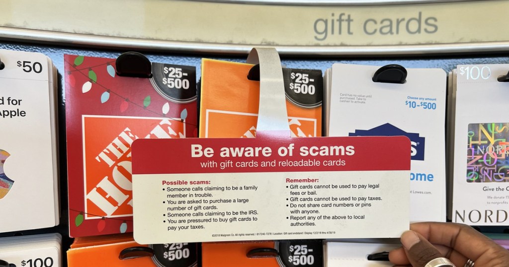 hand holding a warning about gift card scams