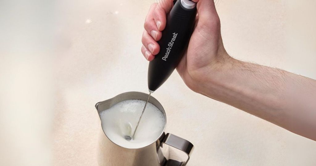 hand using a milk frother