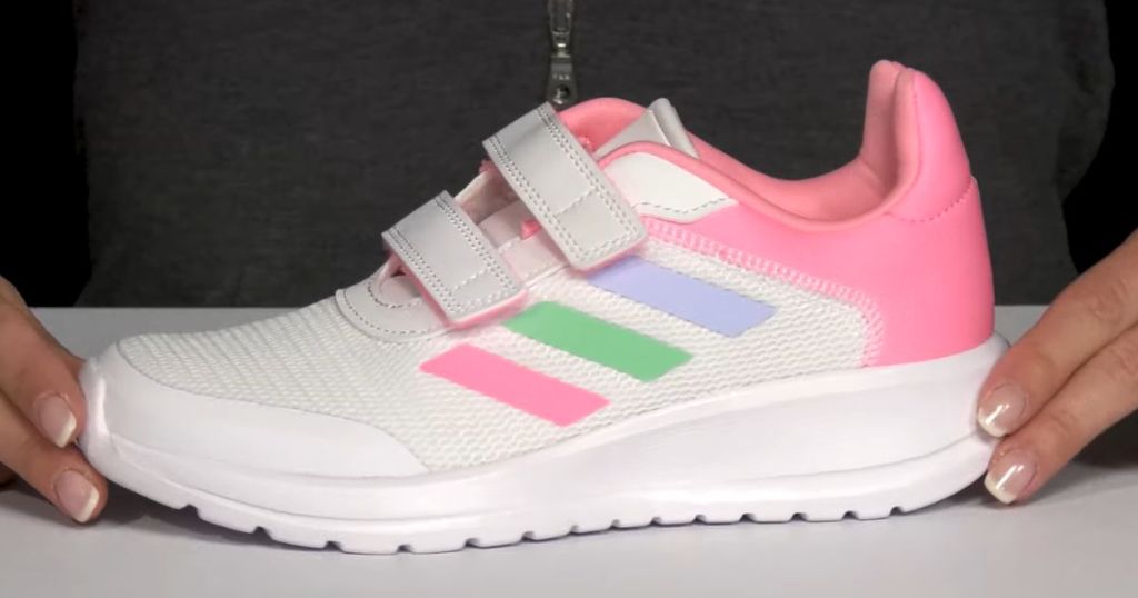 hands holding an Adidas Kids Tensaur white / pink tennis shoe