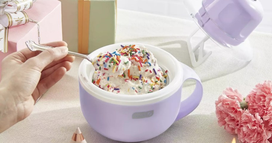 light purple Dash My Mug Ice Cream Maker shown with person' hand holding a spoon eating ice cream from it