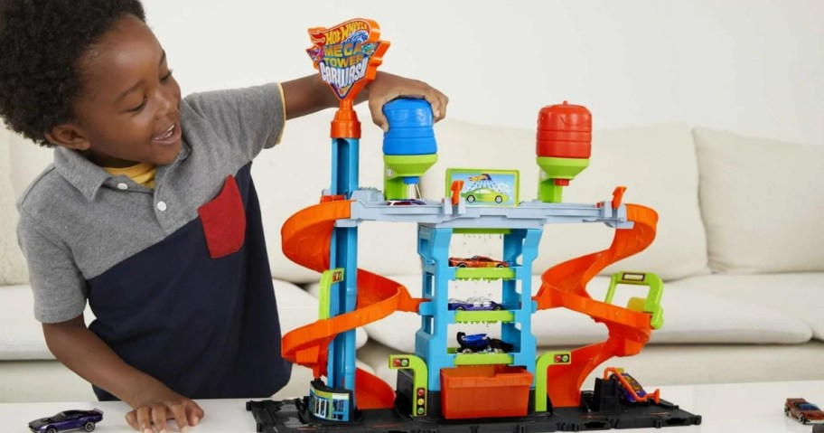 little boy playing a blue, green, orange, and grey Hot Wheels City Mega Car Wash Playset