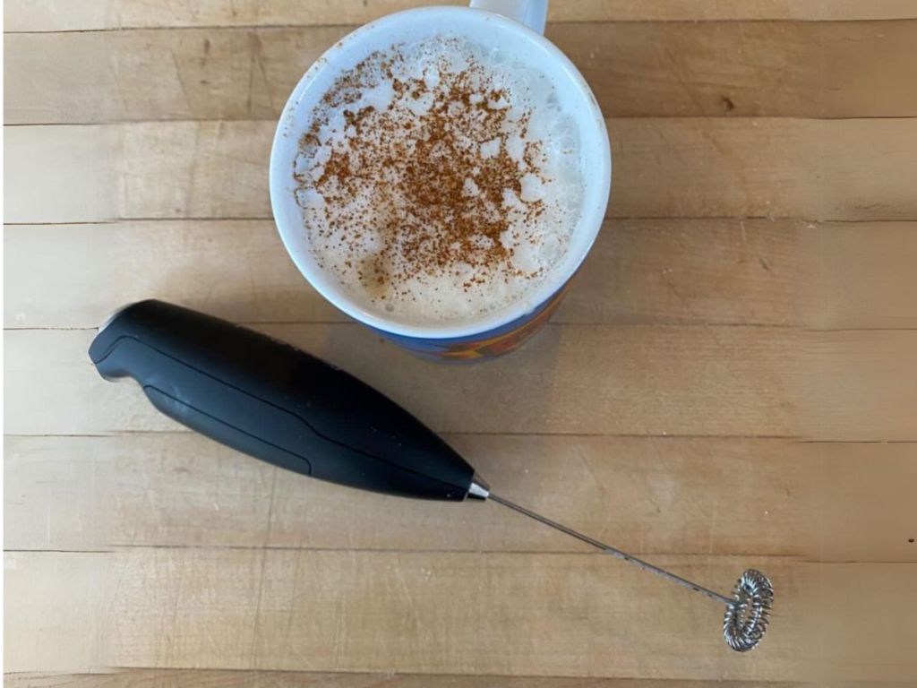 milk frother and cup of coffee sitting on counter