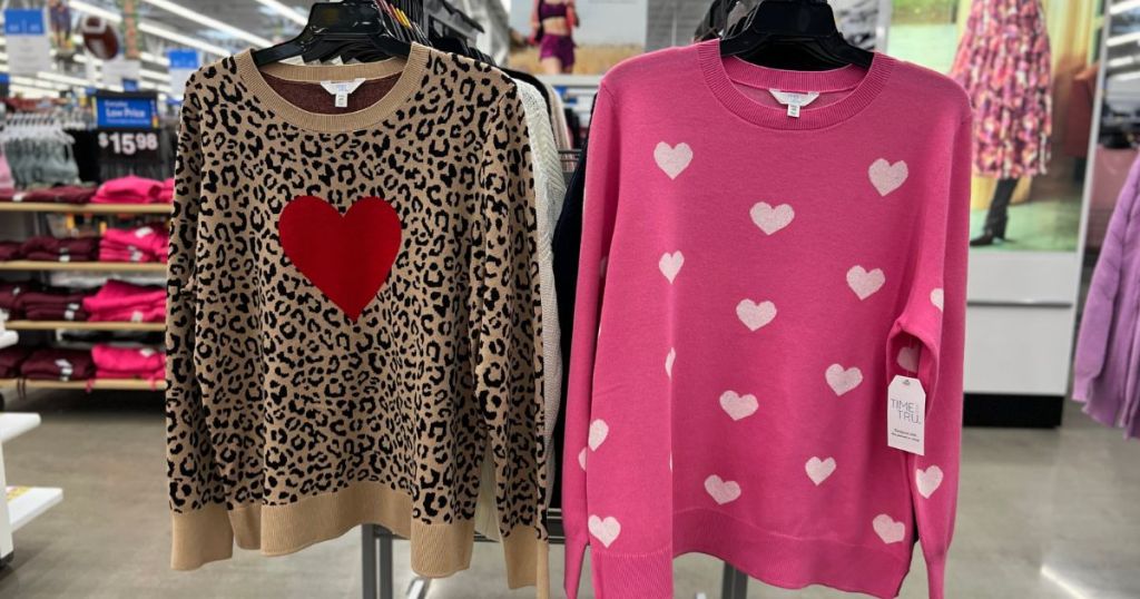 animal print with red heart and pink with white hearts sweaters hanging on rack at Walmart
