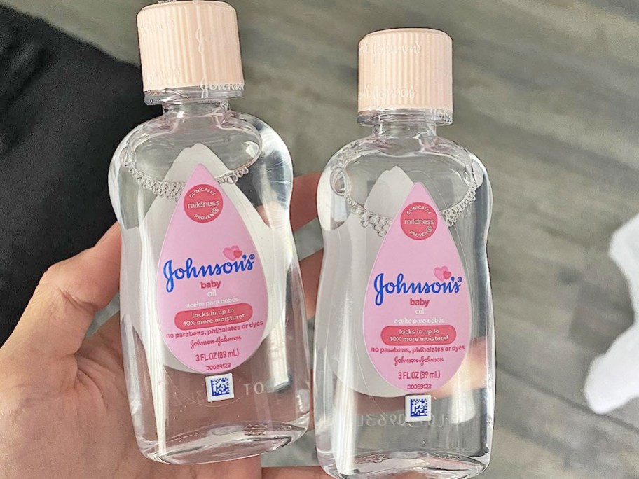 hand holding two bottles of Johnson's Baby Oil
