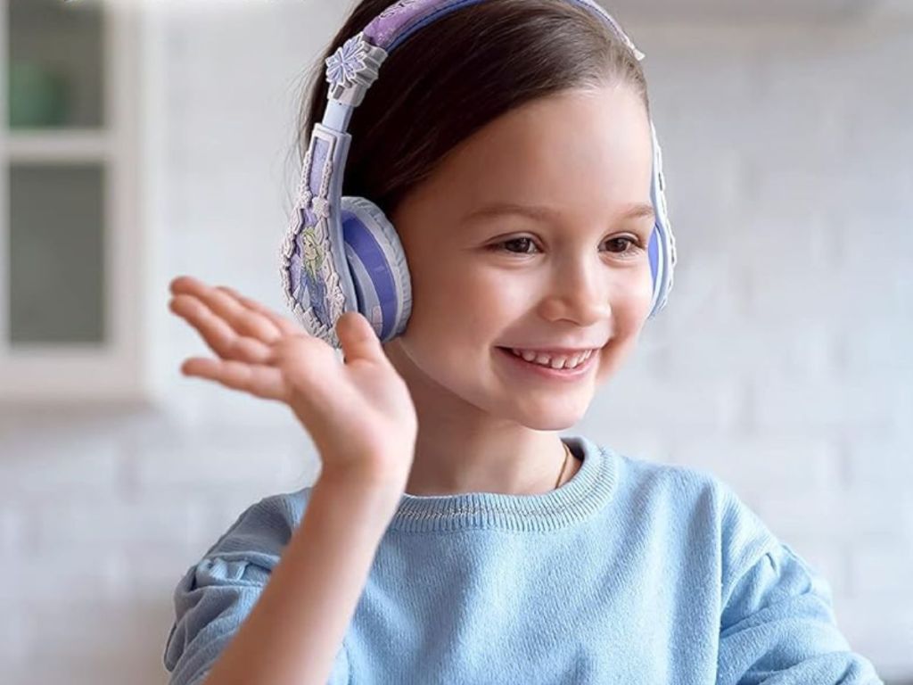 little girl waving while wearing frozen headphones