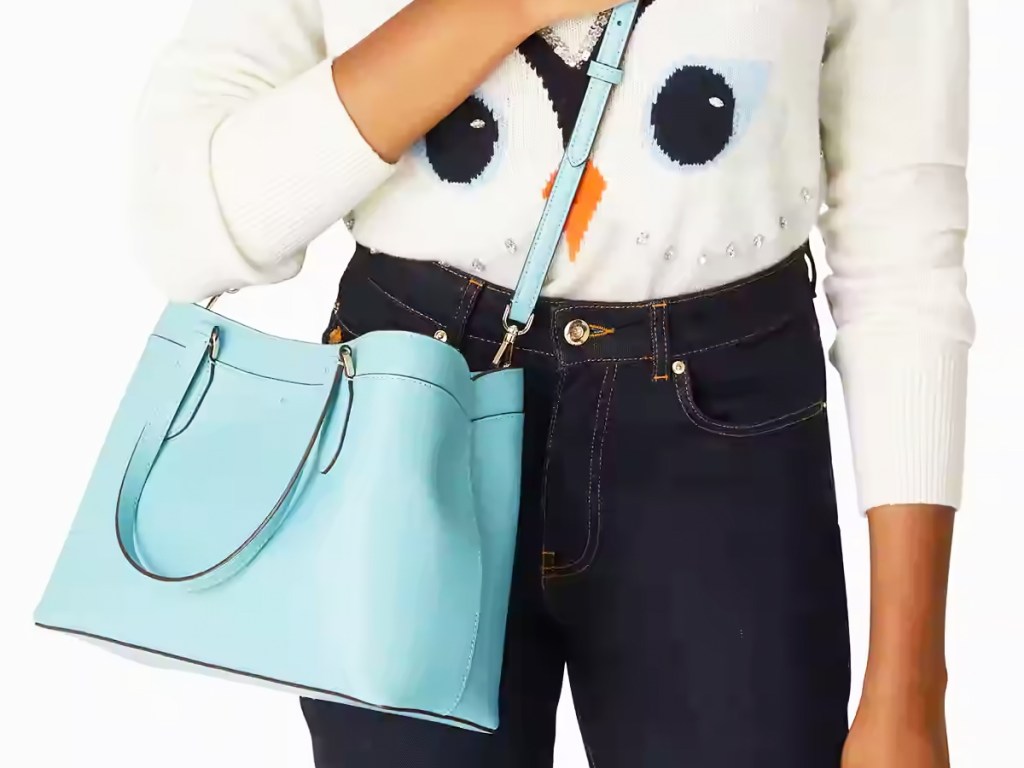 woman in white sweater with dark jeans and blue purse