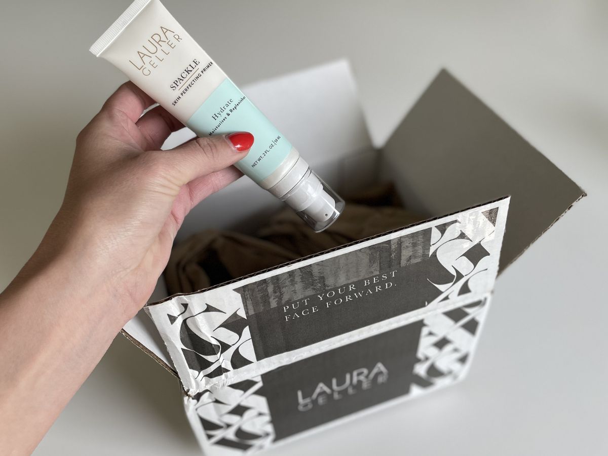 A laura geller shipping box with a tube of Spackle Primer being taken out of it