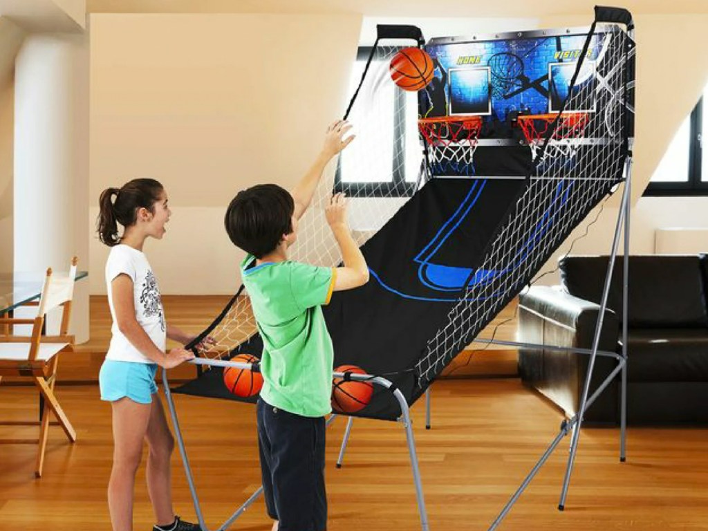 two kids playing with an indoor basketball arcade 