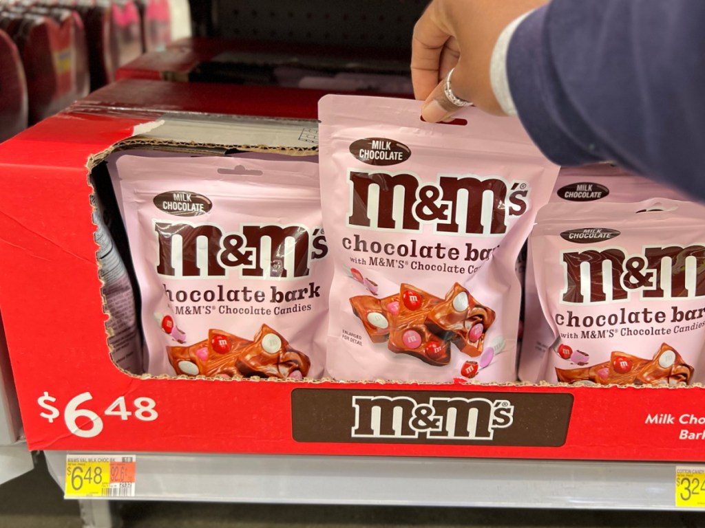 person grabbing bag of M&Ms chocolate bark from walmart store