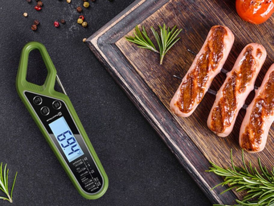 A tray of grilled sausages with a Maestri Home Digital Meat Thermometer next to it