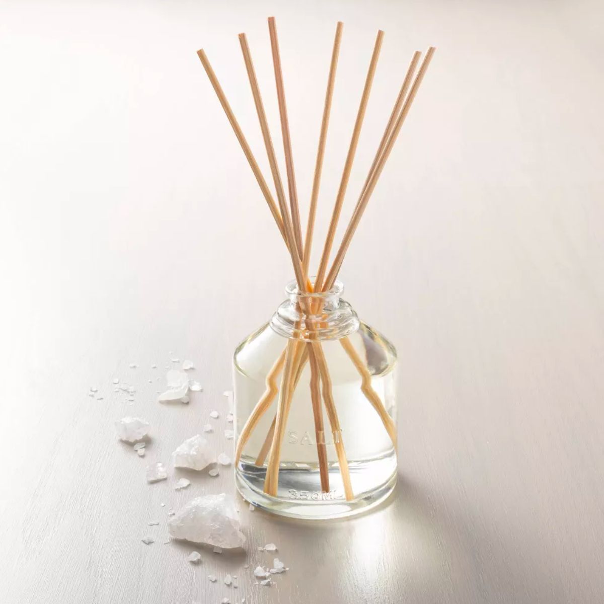 Magnolia Salt Oil Reed Diffuser sitting on a table next to various large salt crystals