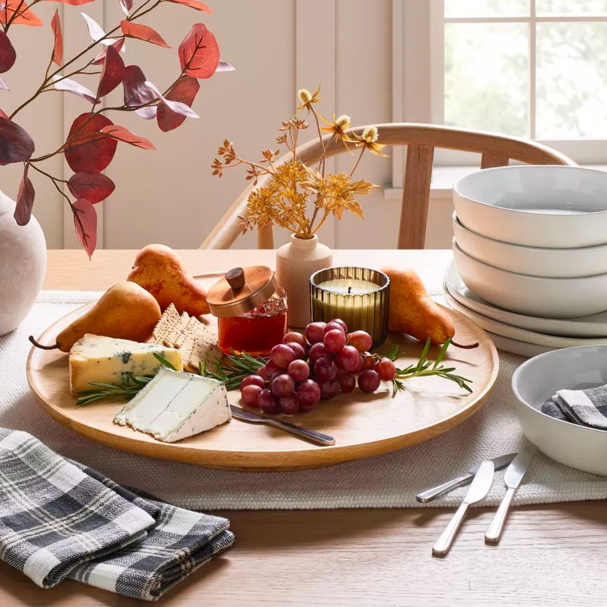 Magnolia Wooden Pedestal Lazy Susan in Natural with a selection of cheeses and grapes sitting on a dining table