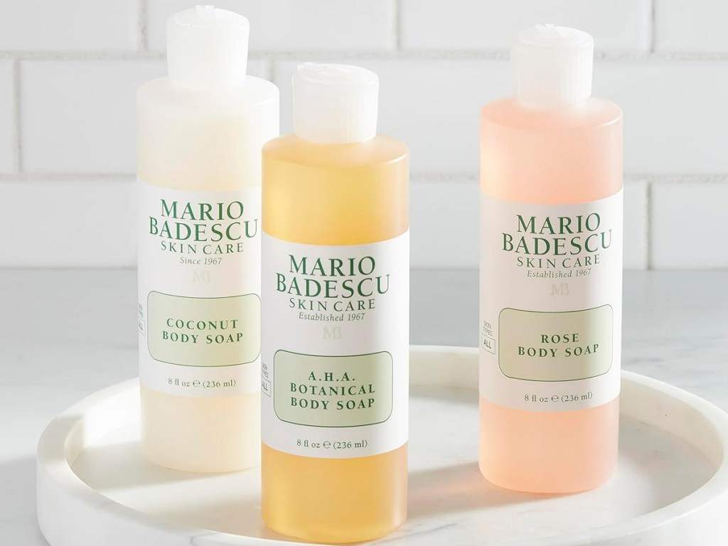 three bottles of Mario Badescu body soaps on white tray
