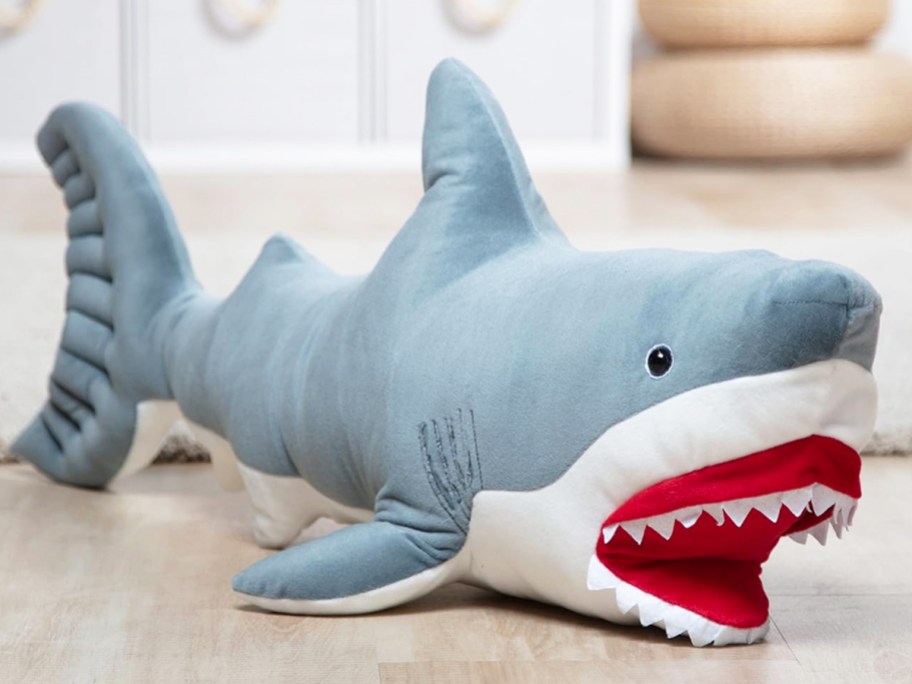 large grey shark stuffed animal laying on floor of playroom