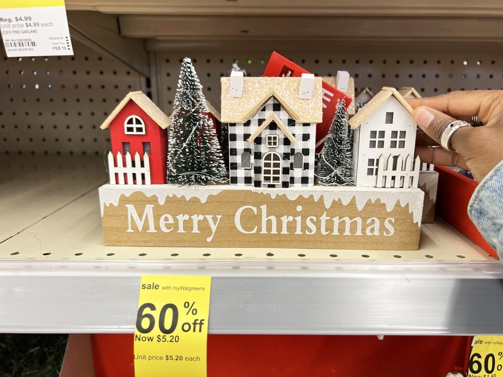 hand touching a Merry Christmas House Sign on store shelf