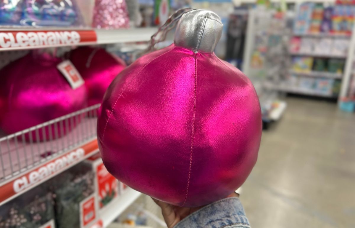 a womans hand holding a hot pink Metallic Christmas Ornament Pillow 9” at five below in the christmas clearance section