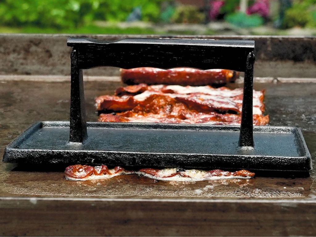 A Mr BBQ griddle press on bacon on a griddle